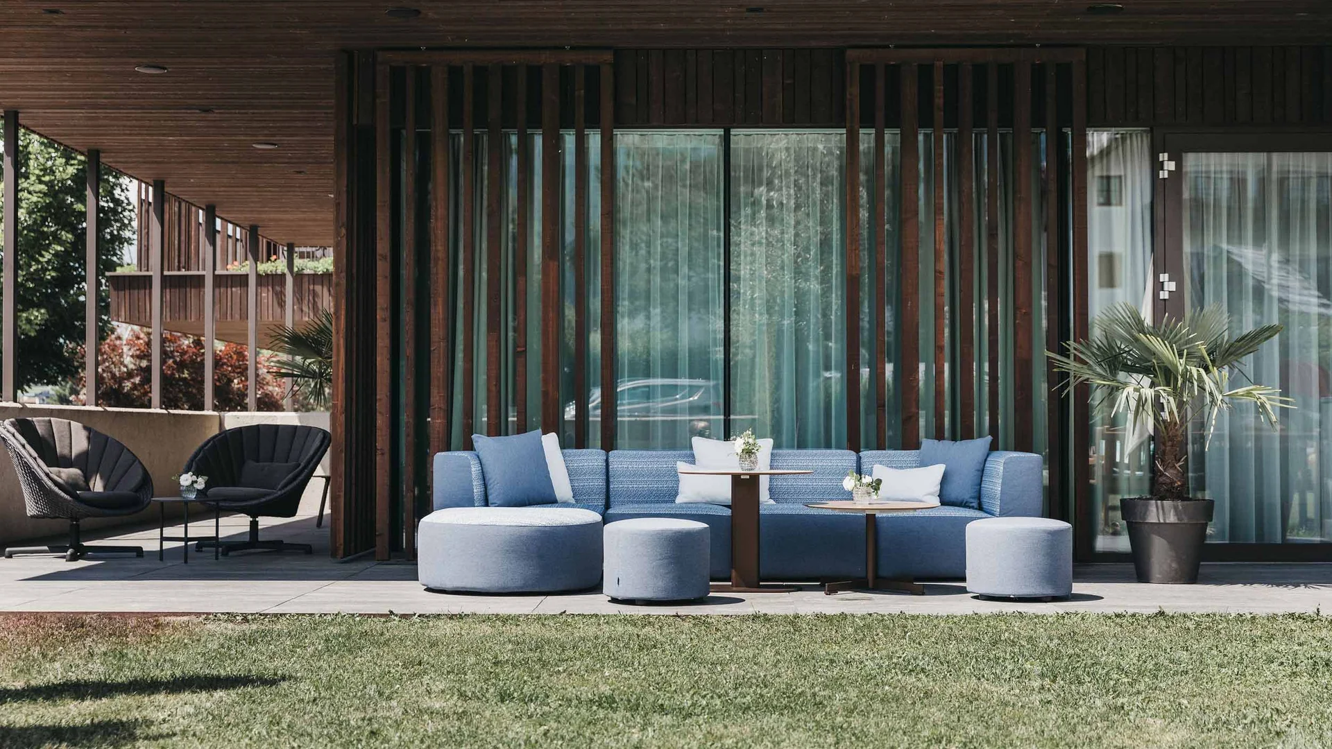 Moderne Terrasse mit blauen Sitzmöbeln und Holzwand