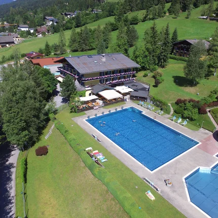 Buitenzwembad met glijbaan naast hotel in groene berglandschap