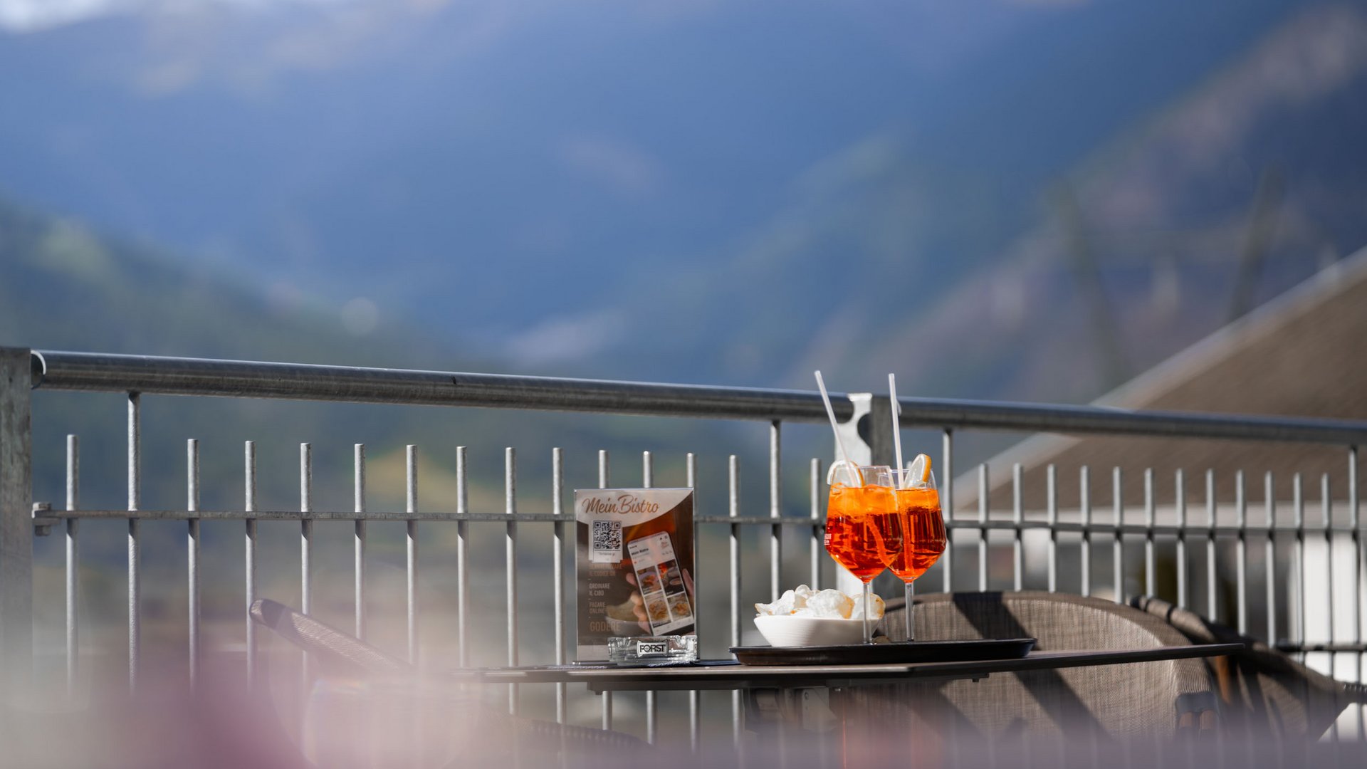 Two Aperol Spritz glasses on a table with mountain view on the terrace