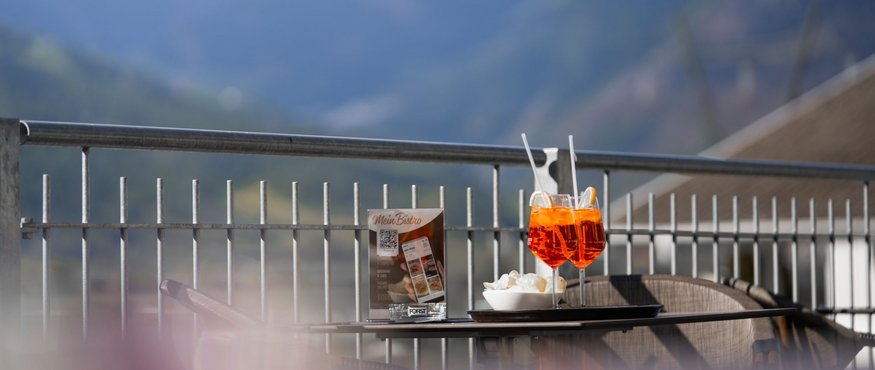 Two Aperol Spritz glasses on a table with mountain view on the terrace