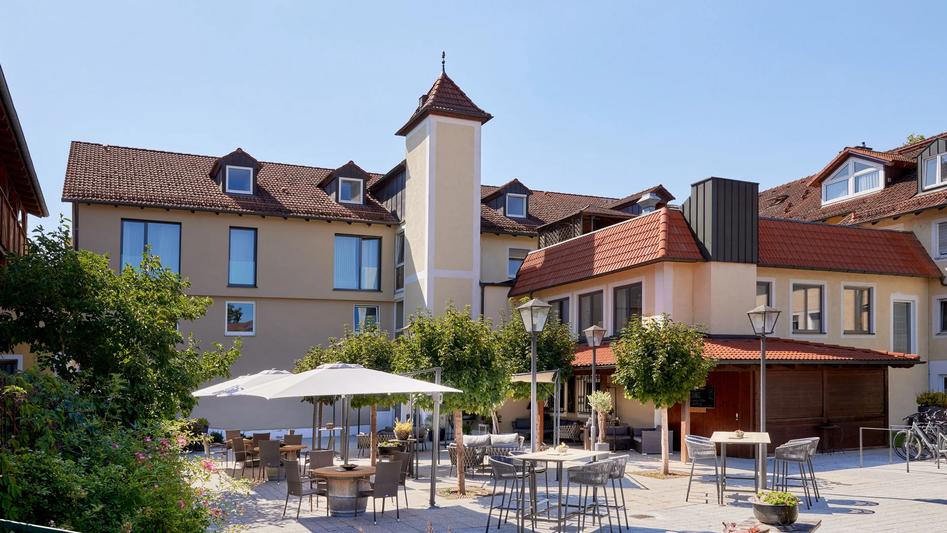 Garden & Spa Hotel das Götzfried **** © Michael Huber Fotographie Buitenruimte van een hotel met tafels, stoelen en parasols op een zonnige dag