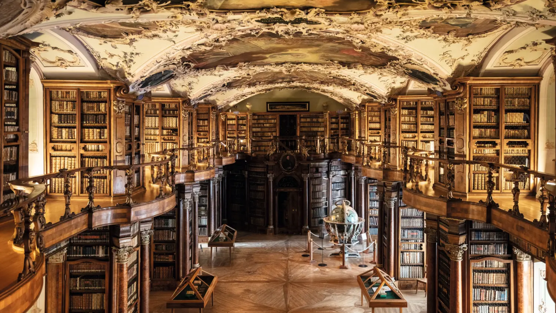 Ornate historic library with ceiling frescoes and wooden bookshelves