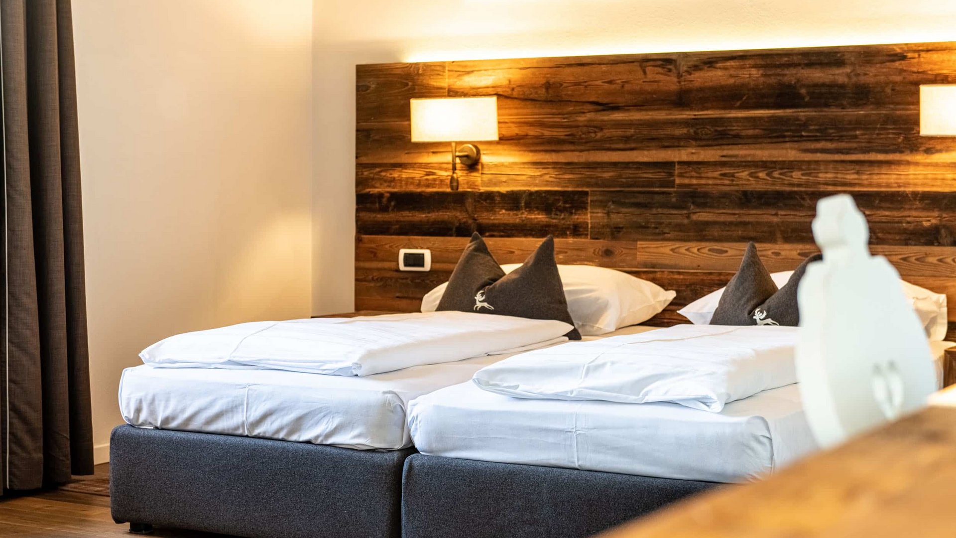 Two single beds with white bedding and wooden wall in twin room