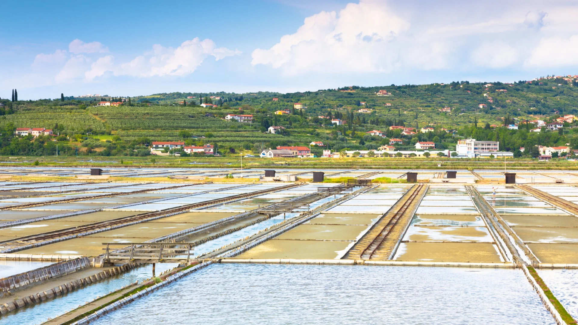 Salt pans with hillside houses and blue sky in background