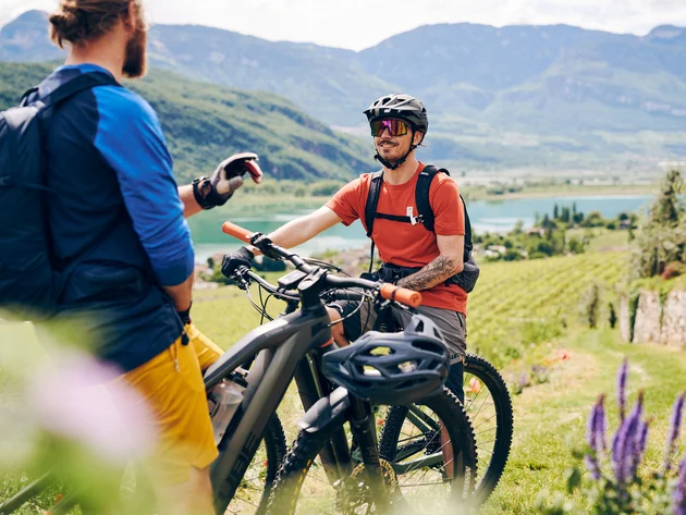 Kulinarisch unterwegs in Tramin © IDM Südtirol - Manuel Ferrigato Zwei Männer mit Mountainbikes in bergiger Landschaft sprechen miteinander