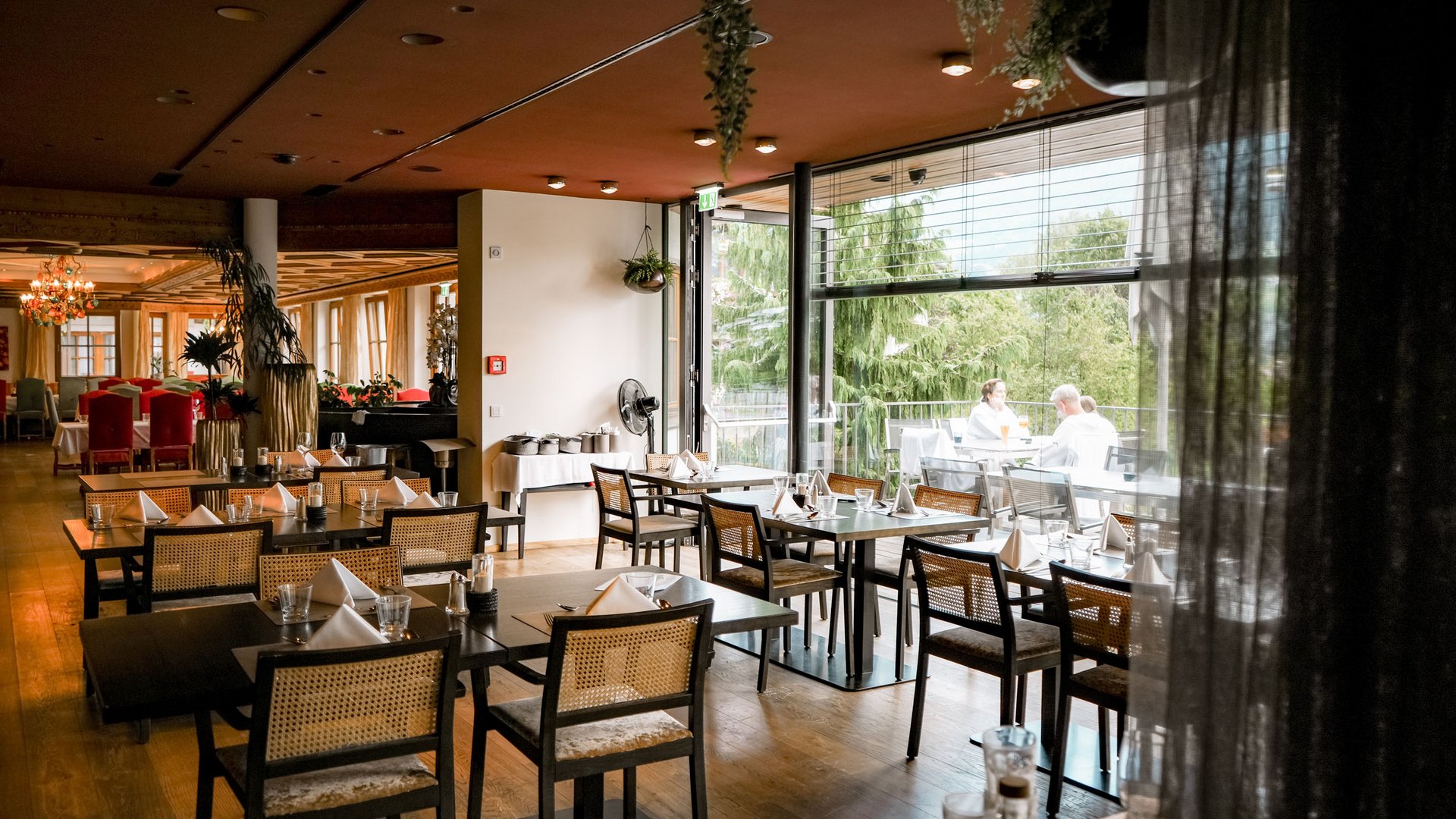 Modern restaurant with set tables and outdoor terrace with guests