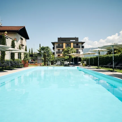 Uitzicht op een buitenzwembad met ligstoelen en parasols voor een gebouw