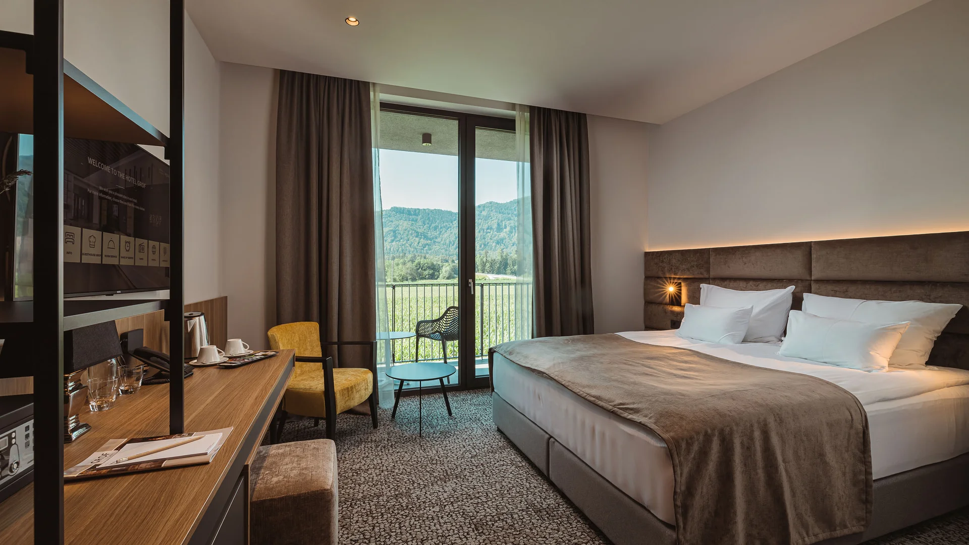 Moderne hotelkamer met tweepersoonsbed en balkon met bergzicht