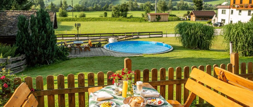 View of breakfast table, pool, and mountains in a rural garden