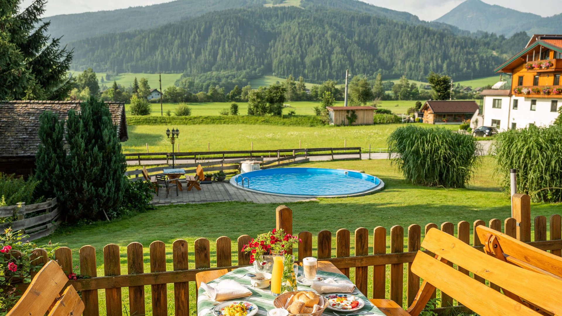 View of breakfast table, pool, and mountains in a rural garden