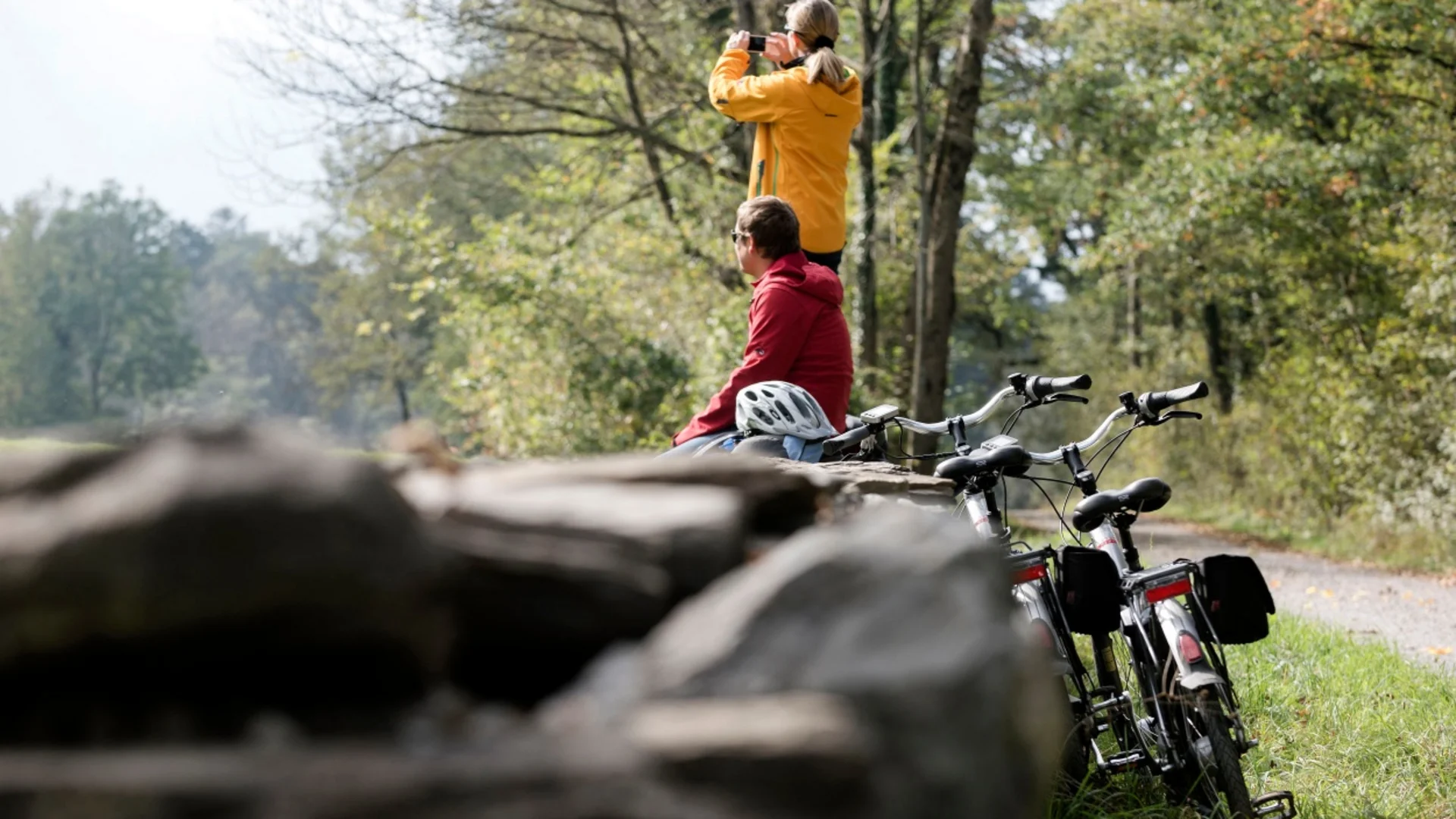 Twee fietsers maken pauze in het bos, een vrouw maakt een foto