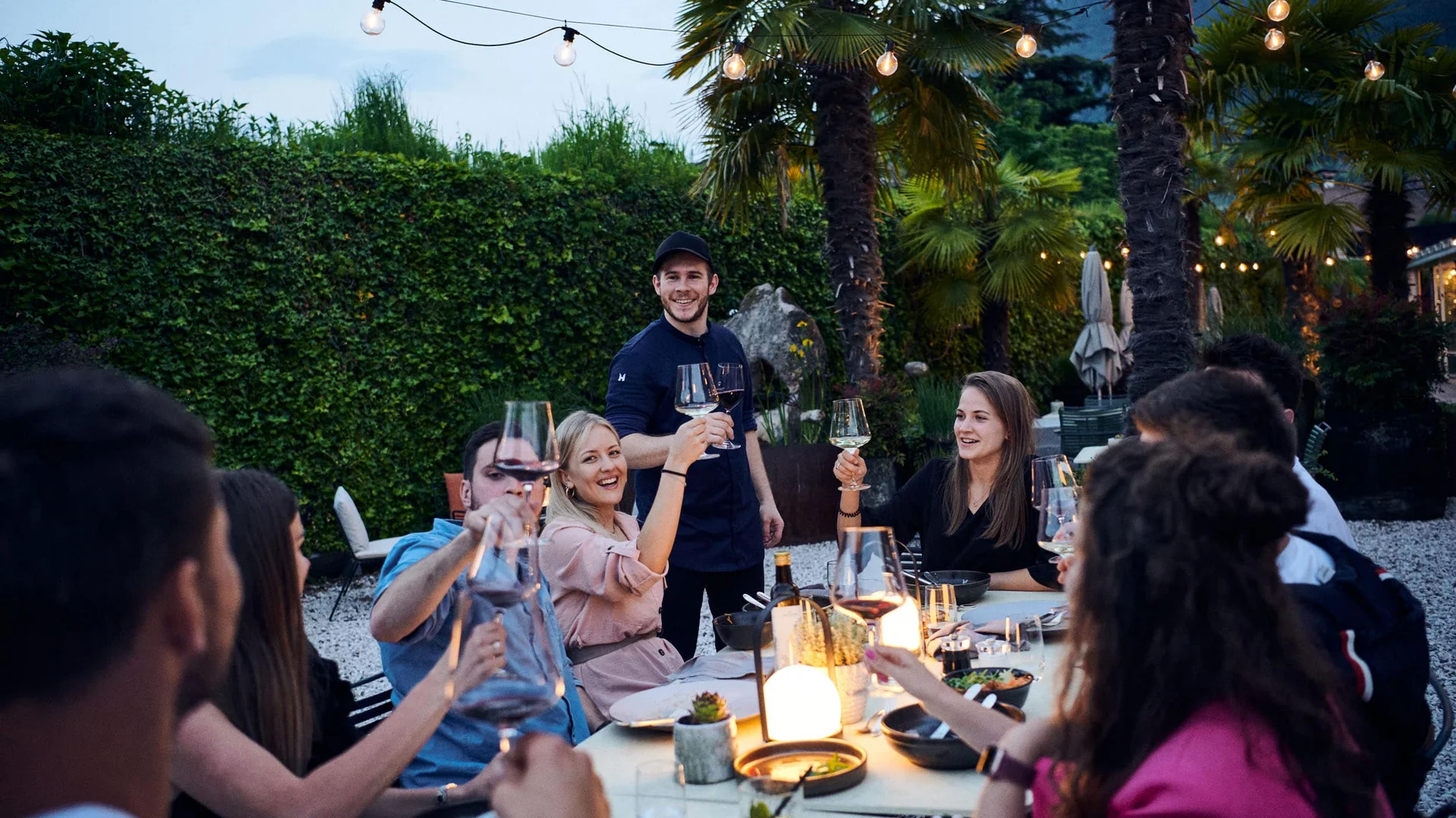 Friends toasting with wine glasses at an outdoor dinner party