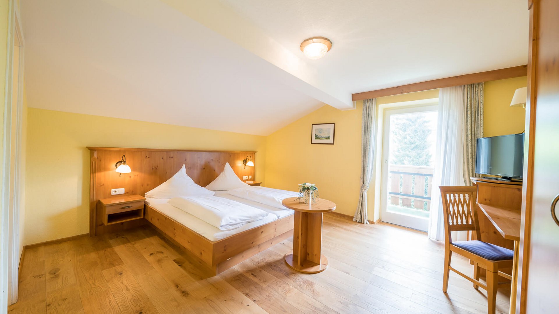 Cozy hotel room with wooden furniture, double bed, and balcony