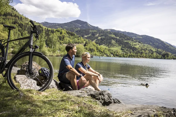 Salzburger Land © Velontour Stel zit aan meer met fiets en uitzicht op bergen