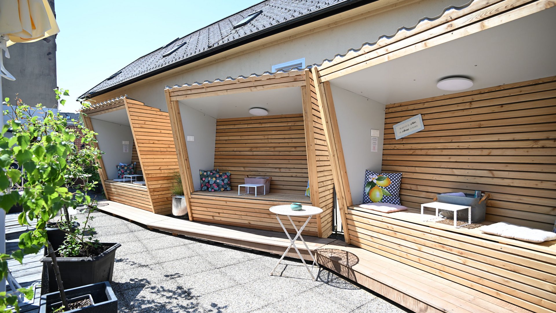 Terrace with wooden seating alcoves and plants in sunny weather