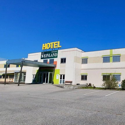 Exterior view of Hotel Weinland with parking lot and clear blue sky