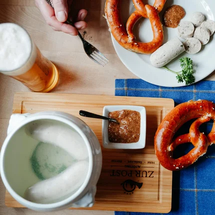 Beierse witte worst met pretzels, zoete mosterd en bier op houten tafel