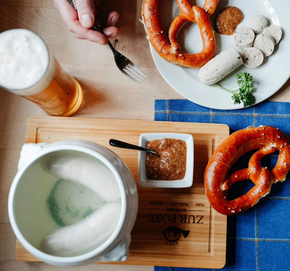 Beierse witte worst met pretzels, zoete mosterd en bier op houten tafel