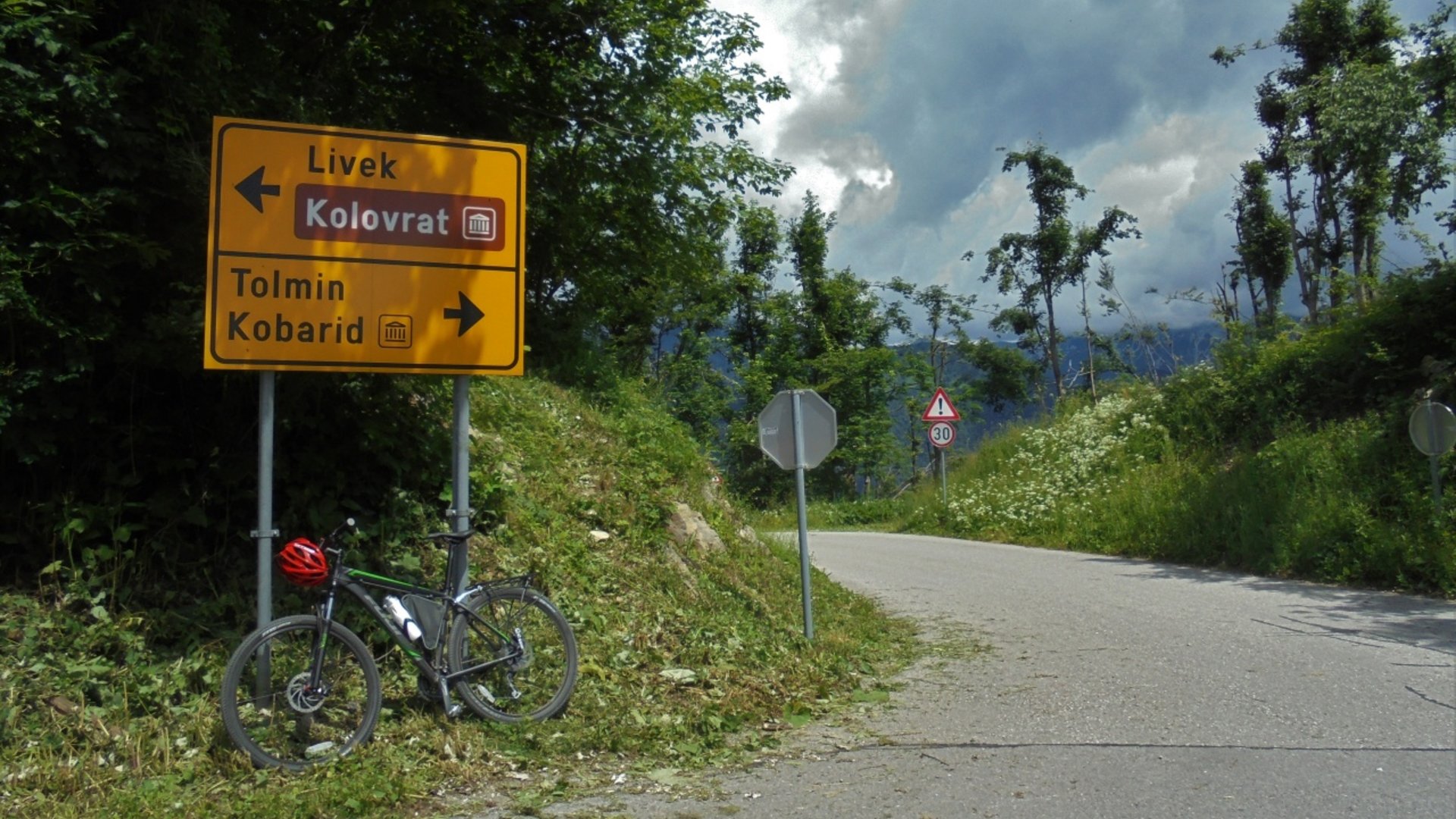 Bicycle leaning on a road sign with directions on a cloudy day
