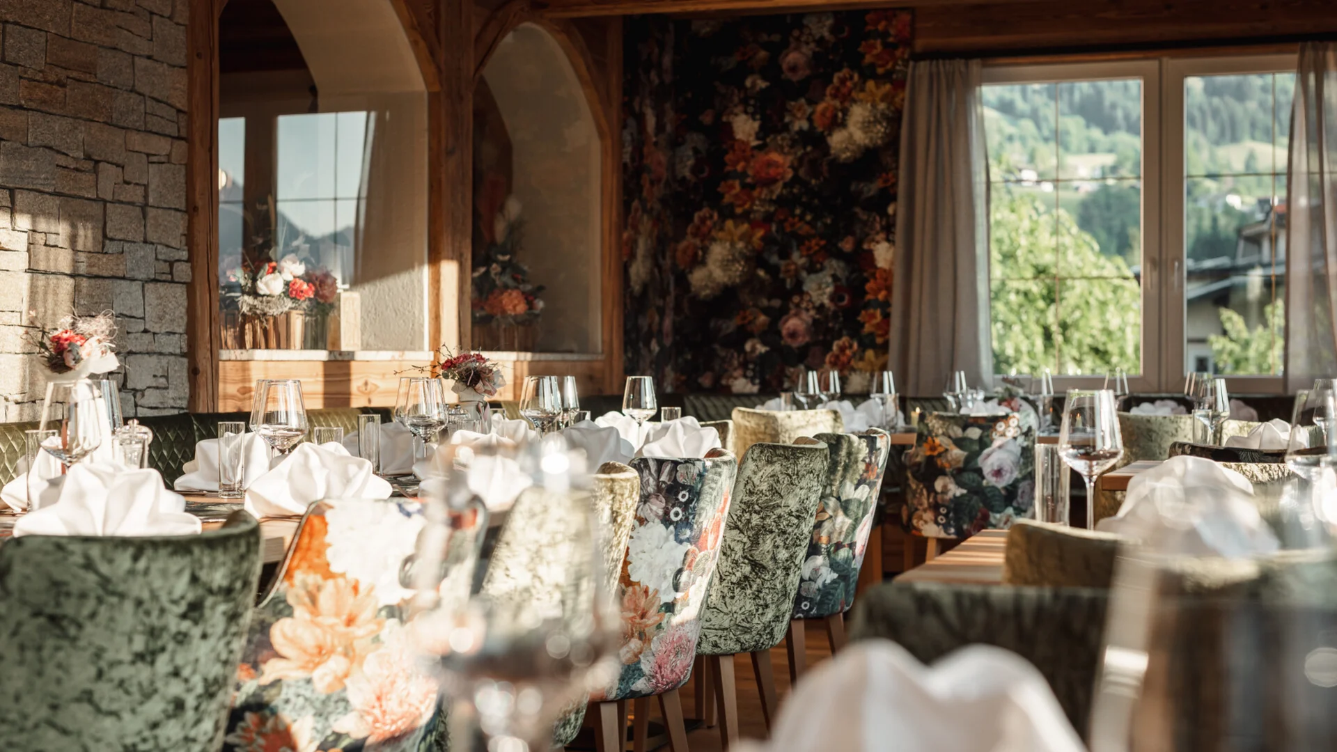 Gemütliches Restaurant mit blumengemusterten Sesseln und eingedeckten Tischen