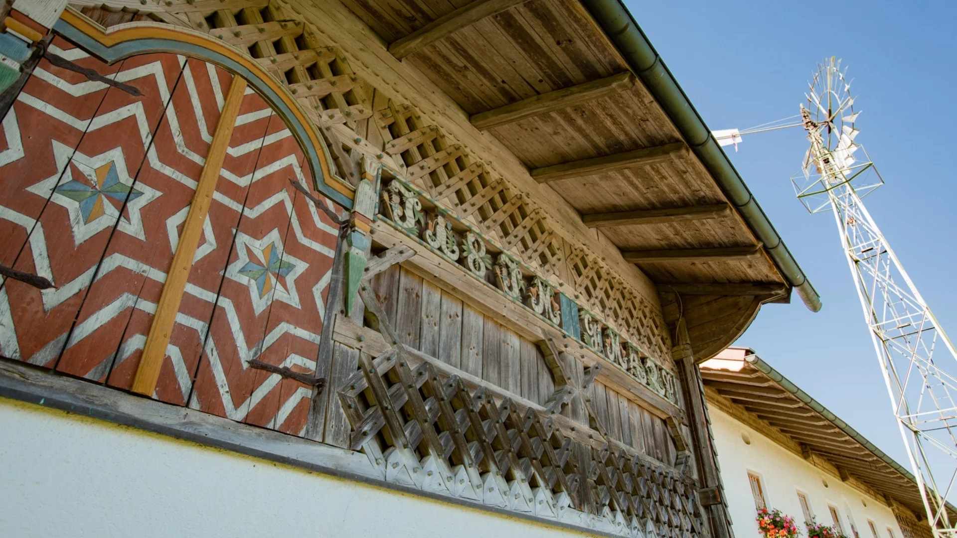 Fassade eines traditionellen Holzhauses mit bemalten Türen und Windrad