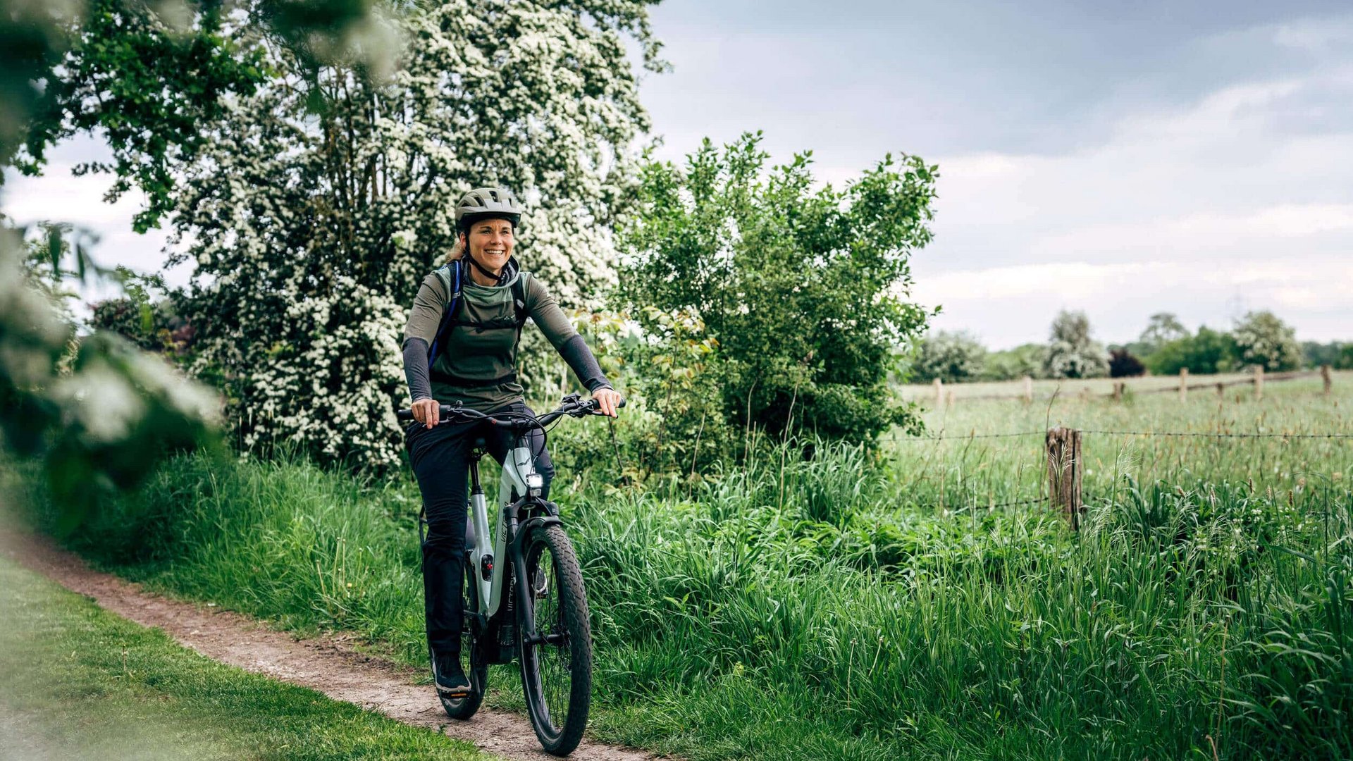 Victoria Woman wearing helmet cycling on a path through green countryside