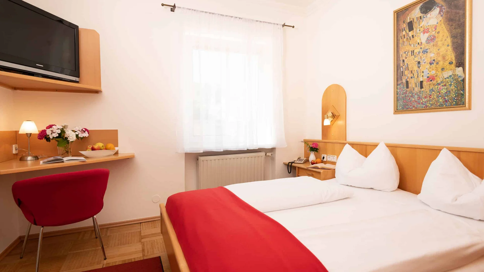 Gezellige hotelkamer met tweepersoonsbed en rode accenten