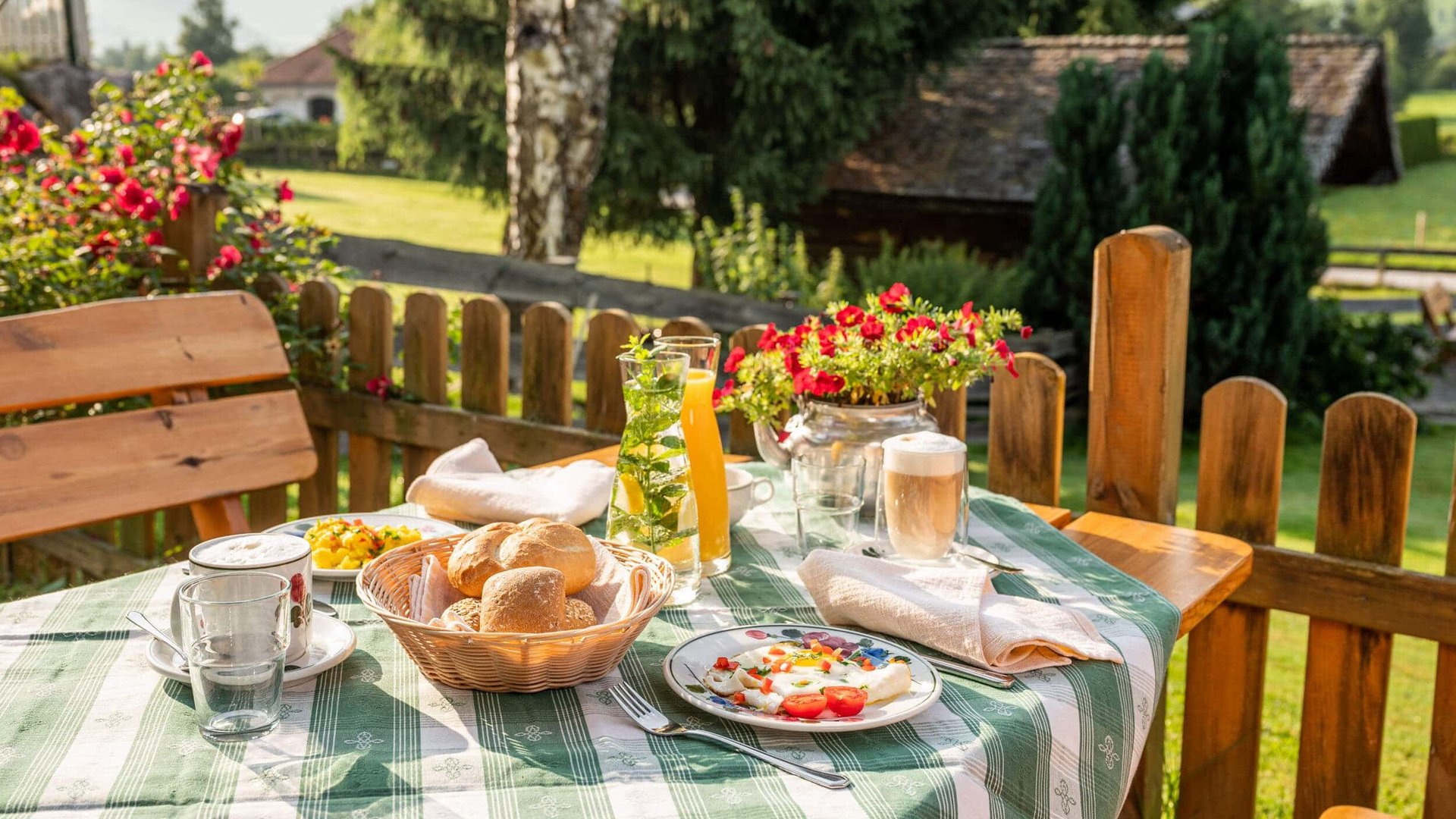 Table with breakfast and flowers on sunny terrace with mountain view