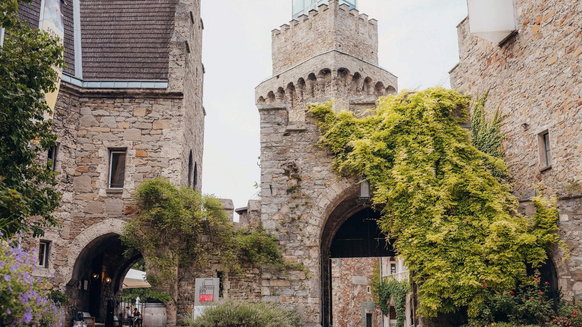 Historic stone gate with green plants climbing the walls on a cloudy day