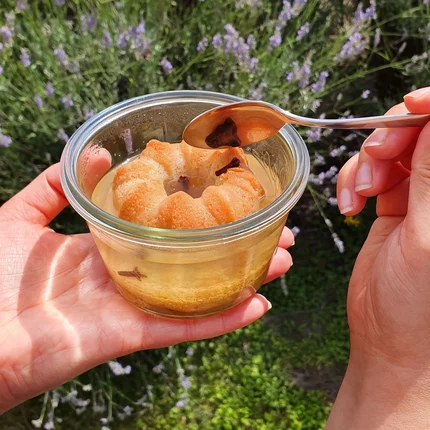 Hand hält Glas mit Wackelpudding und Kuchenring, Löffel berührt Pudding