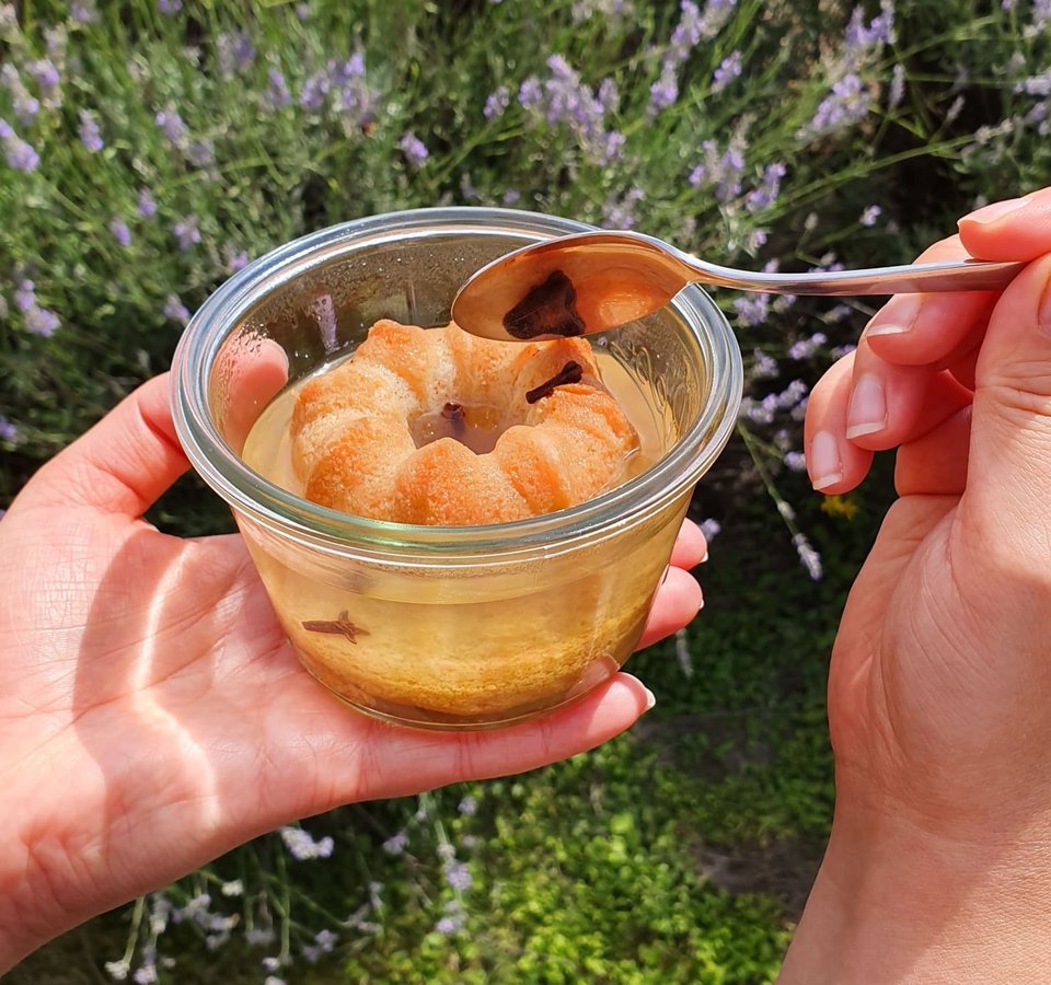 Hand holding glass with jelly and cake ring, spoon touching jelly