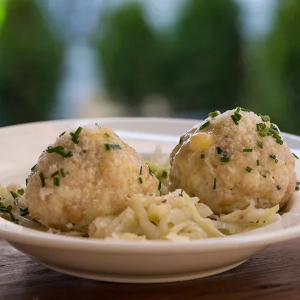 Twee broodknödel met gehakte kruiden op een bord