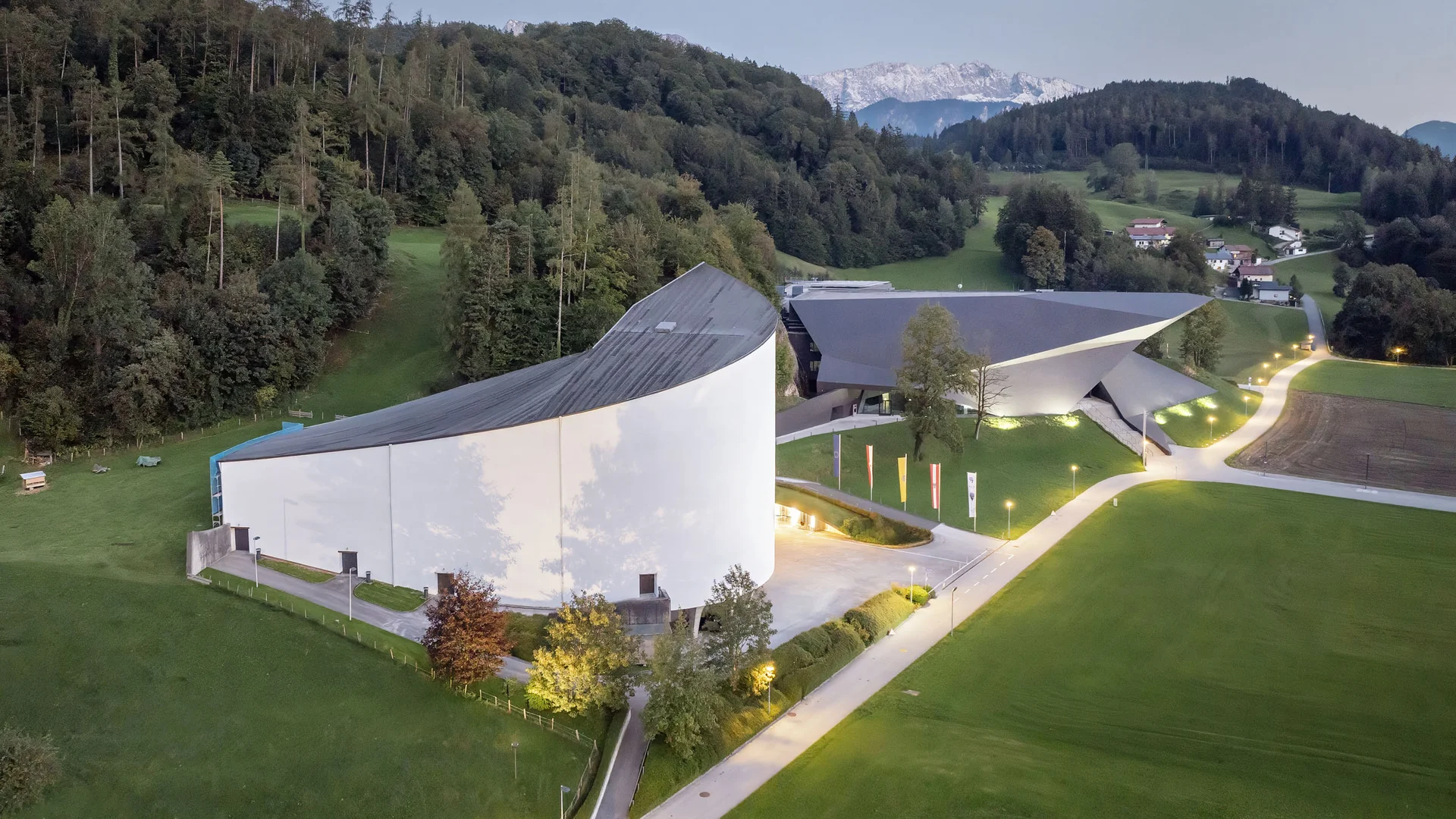 Moderne Gebäude nahe Wald und Bergen bei Dämmerung