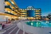 Collective enquiries Lit hotel building with outdoor swimming pool at dusk
