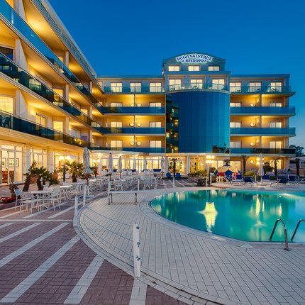 Lit hotel building with outdoor swimming pool at dusk