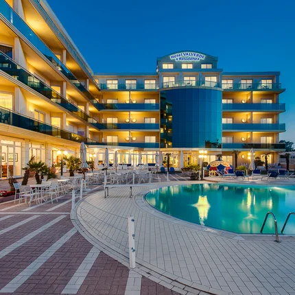 Beleuchtetes Hotel mit Außenpool bei Dämmerung