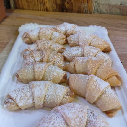 Several mini croissants dusted with powdered sugar on a white tray