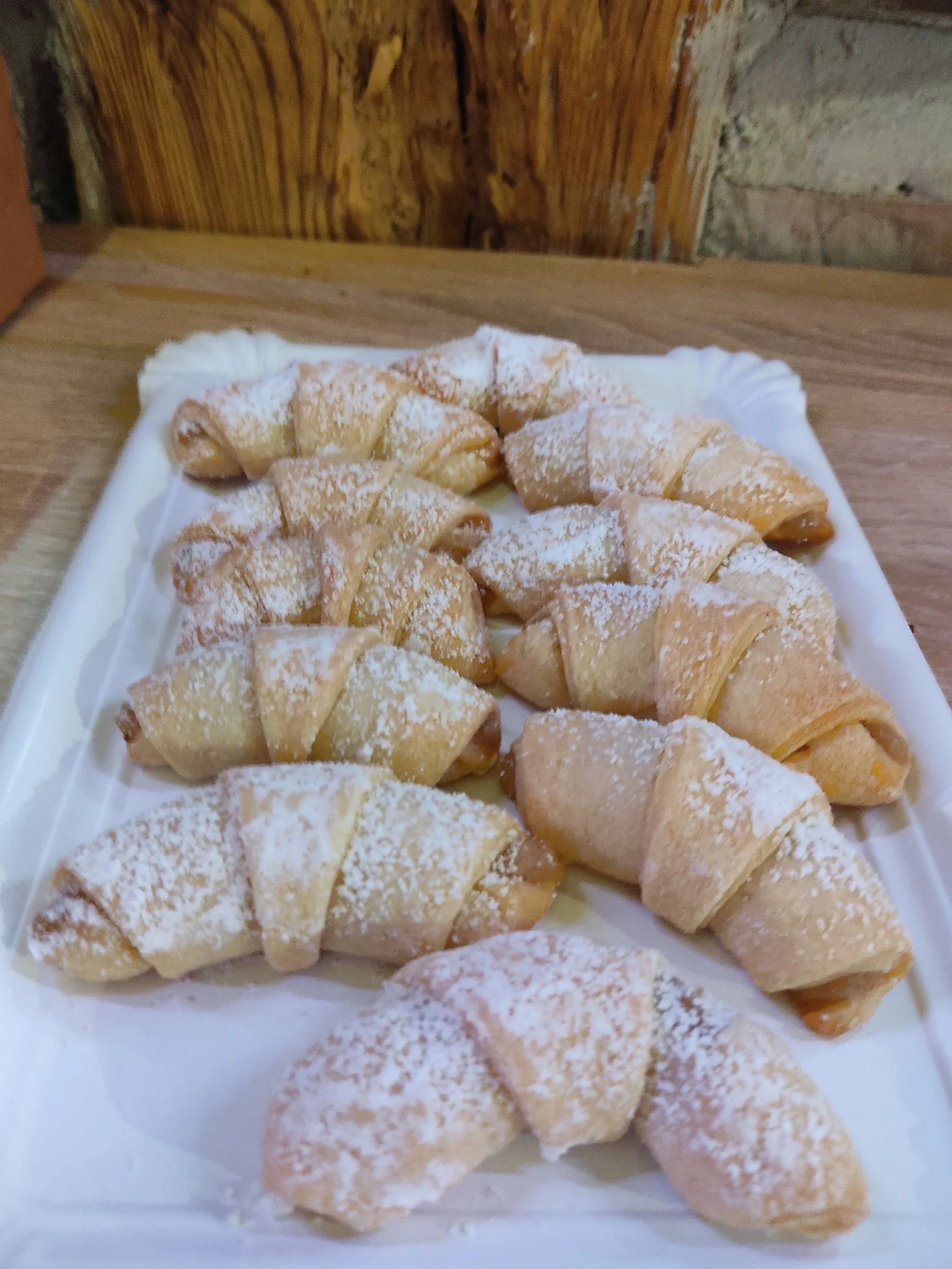 Meerdere mini croissants bestrooid met poedersuiker op een wit dienblad