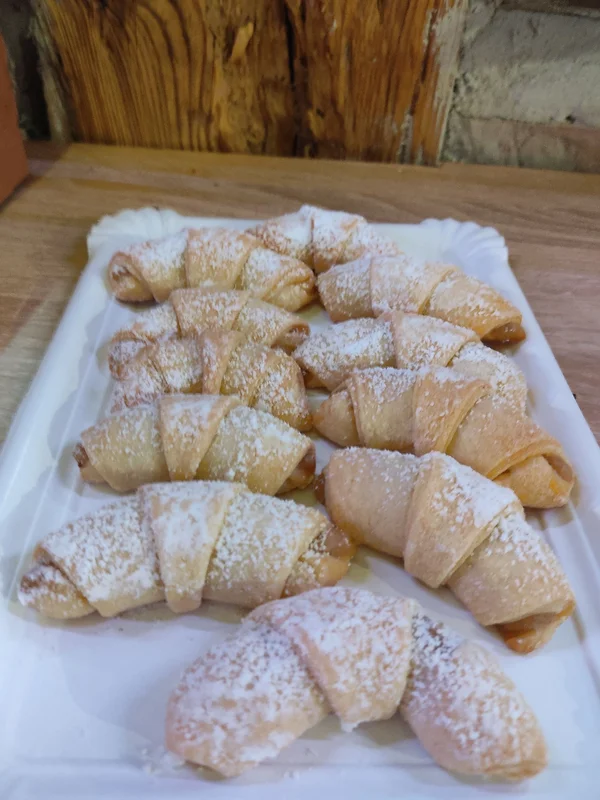 Several mini croissants dusted with powdered sugar on a white tray