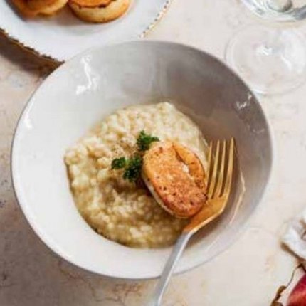 Bowl of risotto with grilled chicken, plate with bread, glass and apple