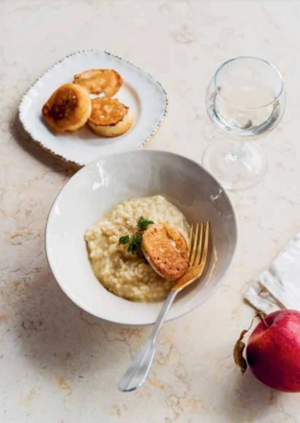 Apfelverjus-Risotto © Restaurant Wasserschloss - Hagenwil Schale mit Risotto, gebratenem Hähnchen, Platte mit Brötchen, Glas und Apfel