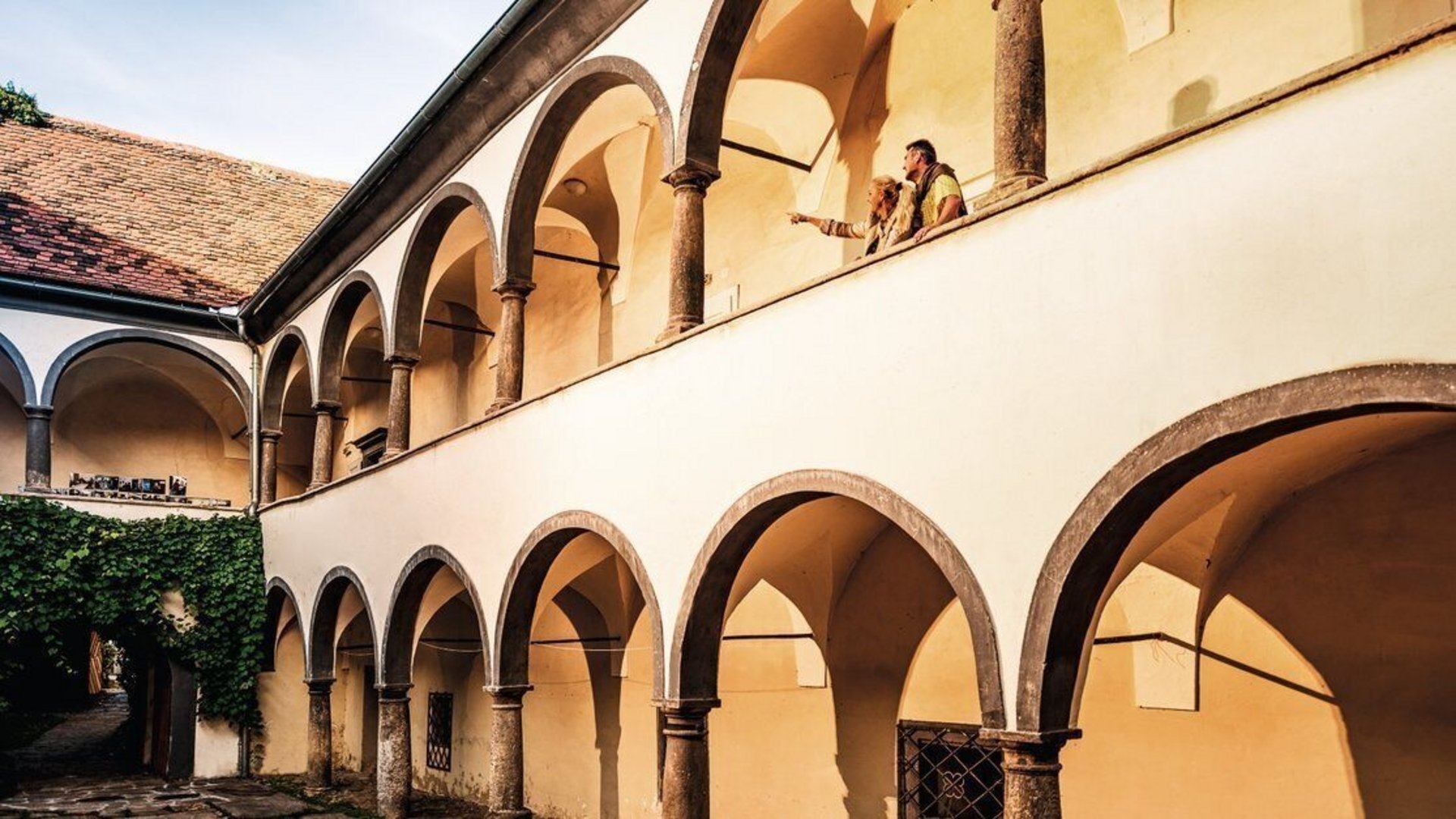Historical building with arches and two people on the balcony