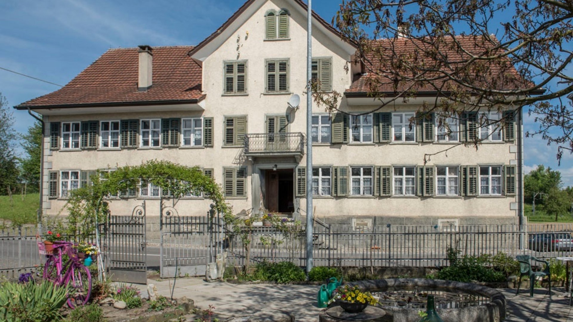 Large traditional house with garden and colorful bicycle by the entrance