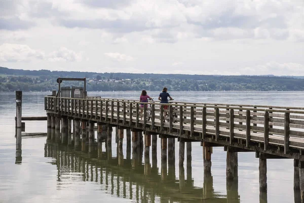 Germany © Velontour Two cyclists on a long wooden pier over calm water