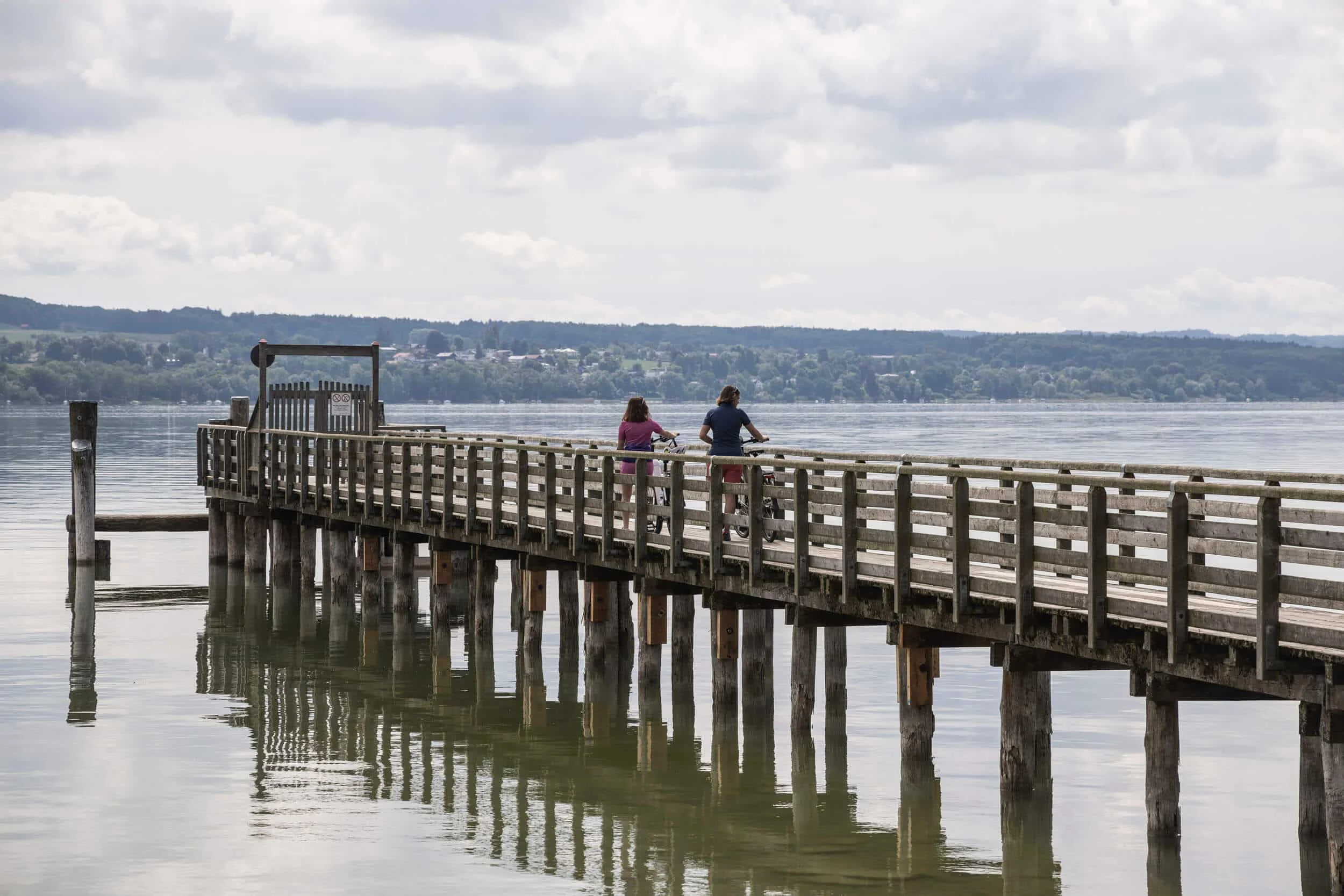 Deutschland © Velontour Zwei Radfahrer auf einem langen Holzsteg über ruhigem Wasser