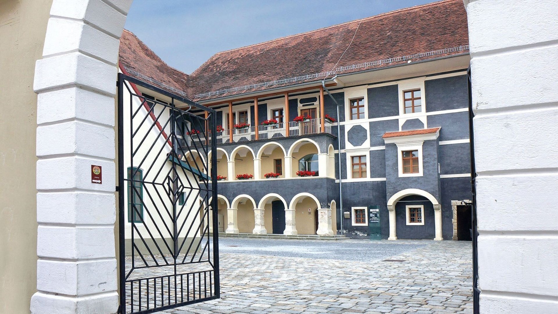 View through gate to cobblestone courtyard and historic building