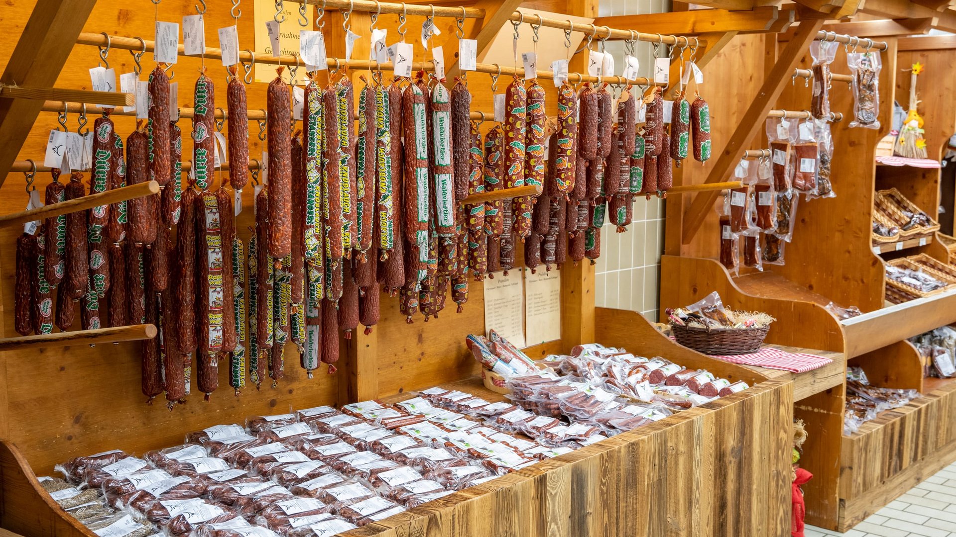 Various sausages hanging and displayed on wooden shelves in a shop