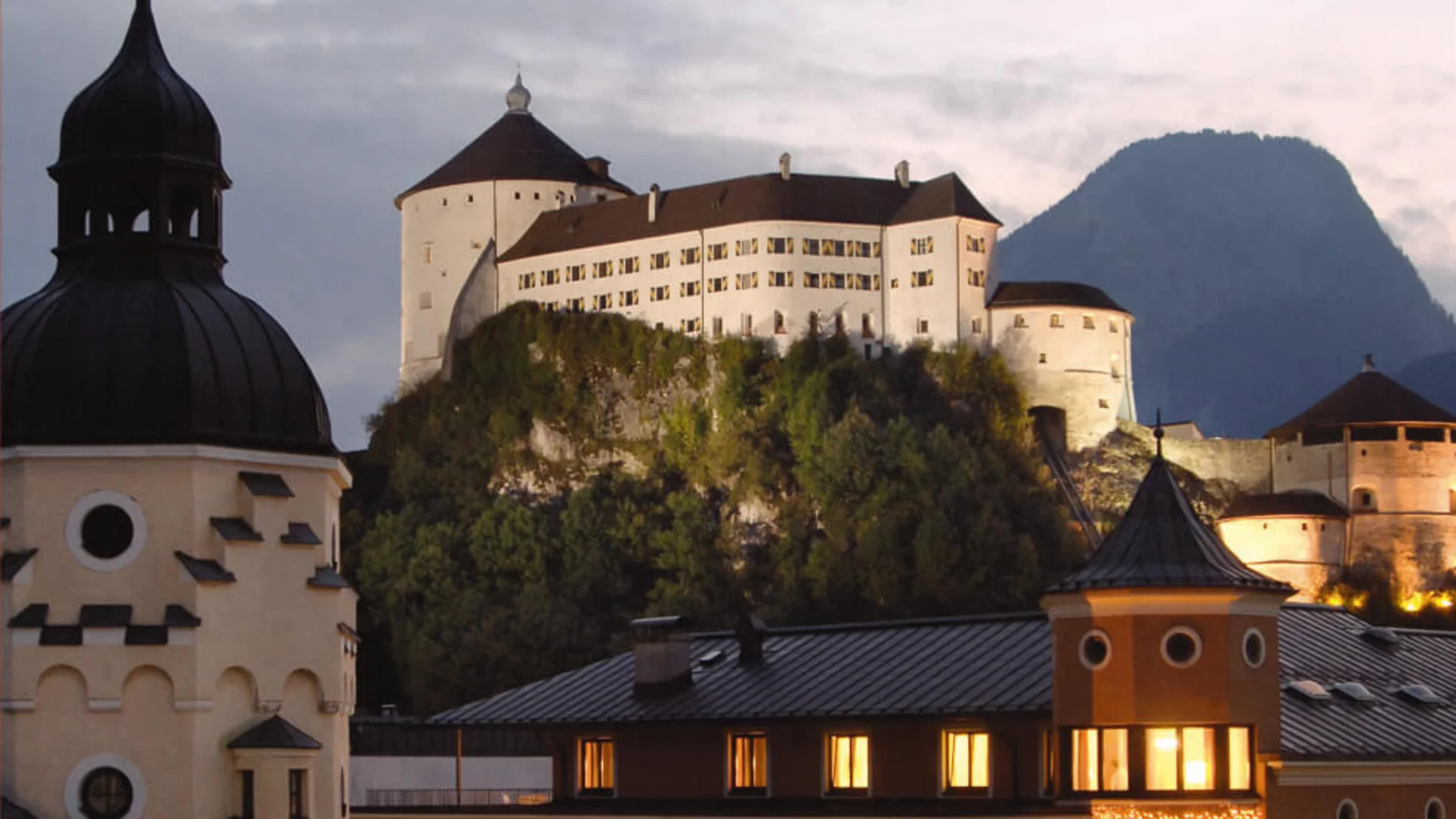 Hotel Andreas Hofer Kufstein **** © Hotel Andreas Hofer Kufstein Beleuchtete Gebäude und Burg auf einem Hügel bei Abenddämmerung