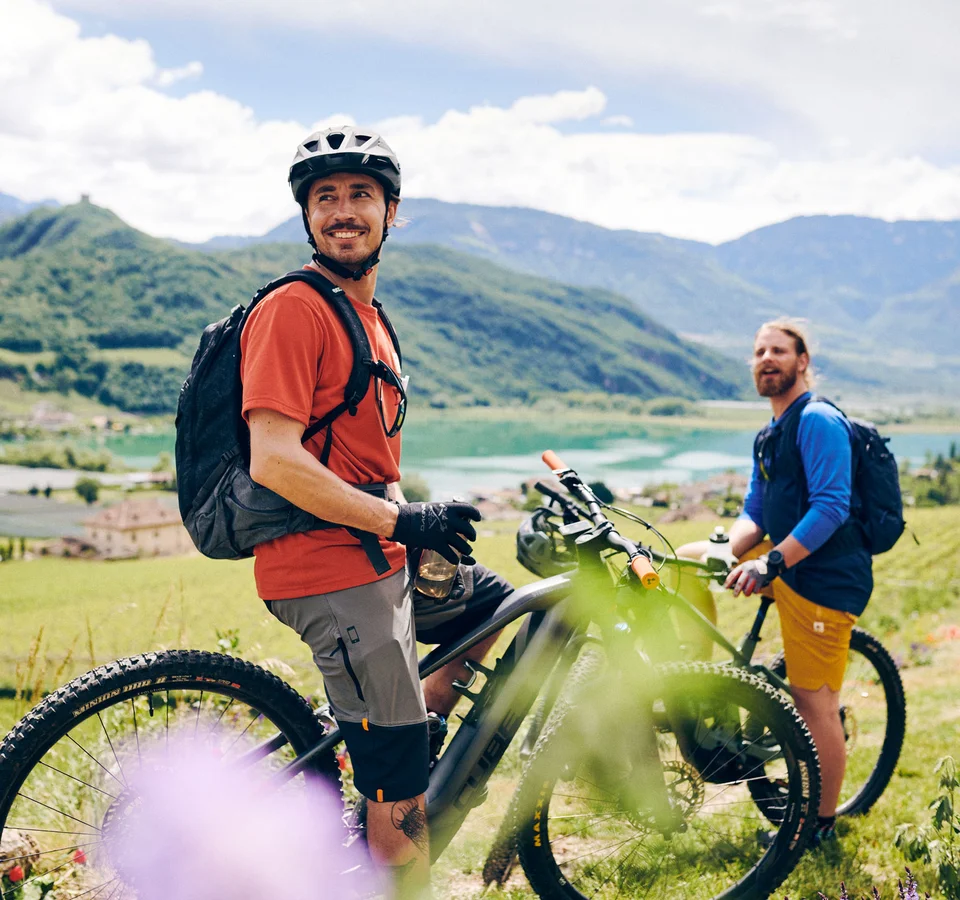 Kulinarisch unterwegs in Tramin © IDM Südtirol - Manuel Ferrigato Zwei Radfahrer in den Bergen mit Blick auf See und Tal