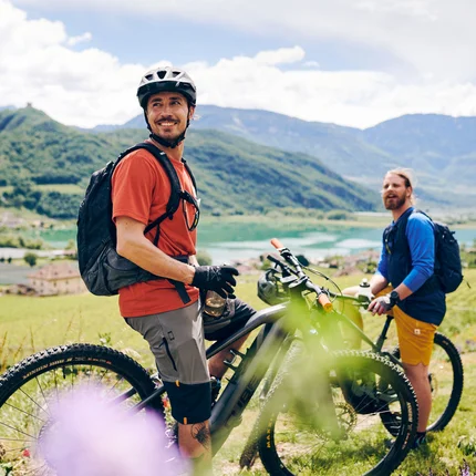Kulinarisch unterwegs in Tramin © IDM Südtirol - Manuel Ferrigato Zwei Radfahrer in den Bergen mit Blick auf See und Tal
